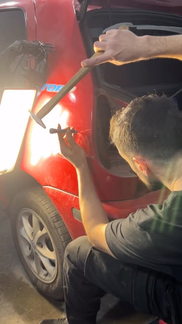 Técnico sacando un bollo de la puerta de un auto